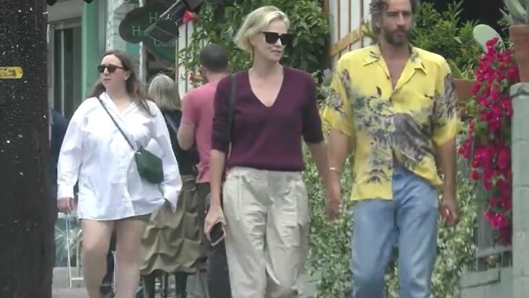 Theron và bạn trai nắm tay, rời khỏi một nhà hàng tại Los Angeles hôm 14/5. Ảnh: BACKGRID