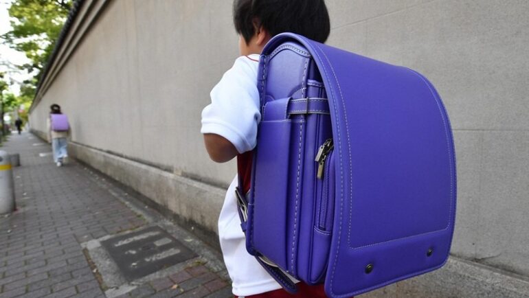 Một học sinh lớp 1 ở Kobe đang đeo chiếc balô chứa toàn bộ sách vở, vật dụng, đồ dùng học tập nặng hơn 6 kg, trên đường về nhà hôm 18/4. Ảnh: Mainichi