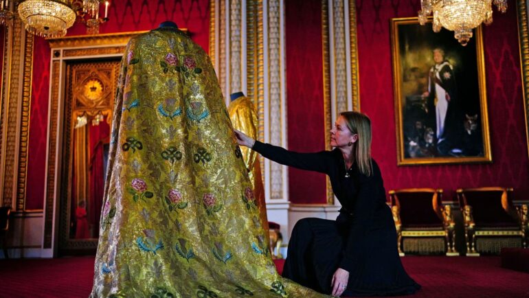 Caroline de Guitaut chỉnh lại Áo choàng Hoàng gia trong Cung điện Buckingham, London, ngày 26/4. Ảnh: Reuters