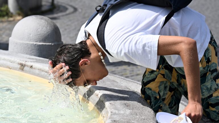 Một cậu bé dội nước lên đầu làm mát ở đài phun nước tại quảng trường Piazza del Popolo ở Rome, Italy, ngày 18/7. Ảnh: AFP