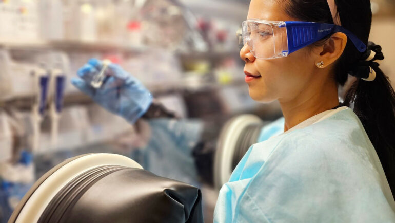 TS Phụng làm việc trong buồng chân không, trong quy trình lắp ráp pin cúc áo. Ảnh: NVCC