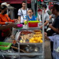 Người dân mua đồ tại một quầy hàng rong ở Bangkok (Thái Lan). Ảnh: Reuters