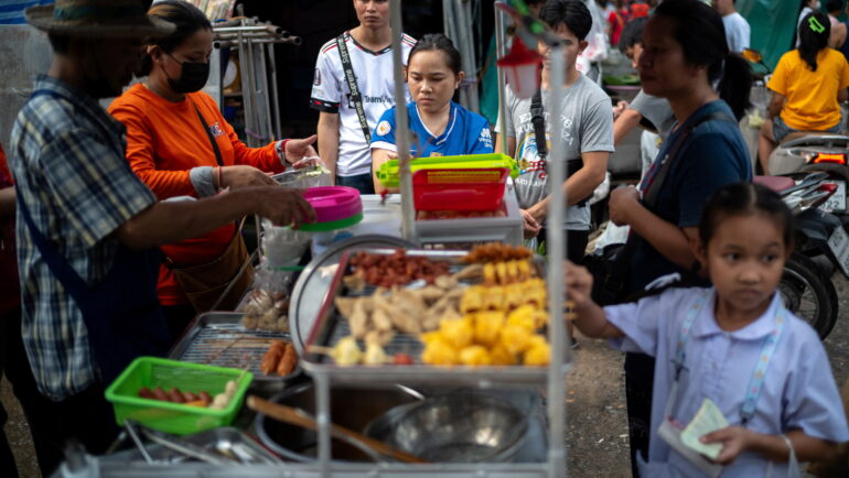 Người dân mua đồ tại một quầy hàng rong ở Bangkok (Thái Lan). Ảnh: Reuters