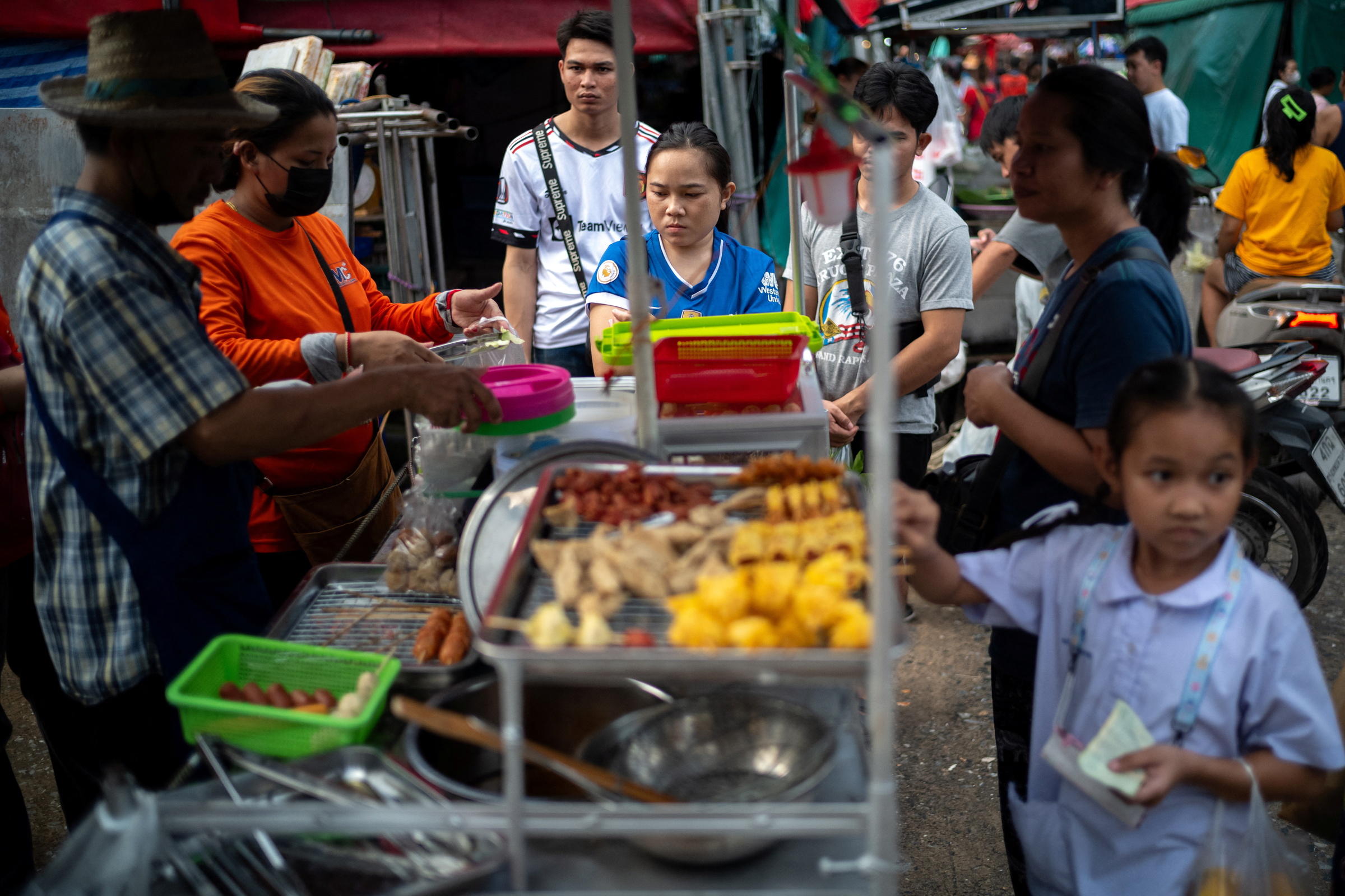 Người dân mua đồ tại một quầy hàng rong ở Bangkok (Thái Lan). Ảnh: Reuters