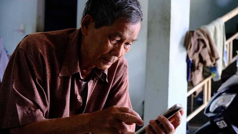 Một người lớn tuổi ở Đà Nẵng làm quen với sử dụng điện thoại thông minh. Ảnh: Nguyễn Đông