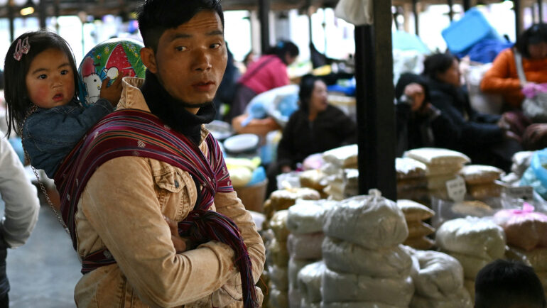 Một người đàn ông địu con bán hàng tại chợ ở Thimpu, thủ đô Bhutan, hồi tháng 1. Ảnh: AFP