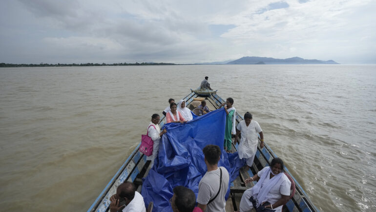 Đội y tế căng bạt và đỡ đẻ cho Jahanara Khatoon trên chiếc thuyền giữa dòng lũ sông Brahmaputra, bang Assam, đông bắc Ấn Độ ngày 3/7. Ảnh: AP