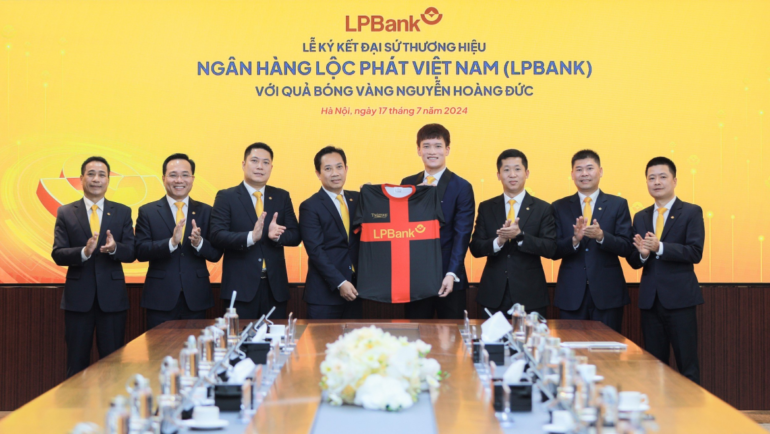 Ông Lê Minh Tâm, Phó chủ tịch thường trực Hội đồng quản trị LPBank (trái) trao trang phục cho cầu thủ Hoàng Đức tại lễ công bố đại sứ thương hiệu Ngân hàng Lộc Phát Việt Nam (phải). Ảnh: LPBank