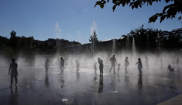 Người dân giải nhiệt bên dưới đài phun nước ở công viên Madrid Rio tại Madrid hôm 23/7. Ảnh: AFP