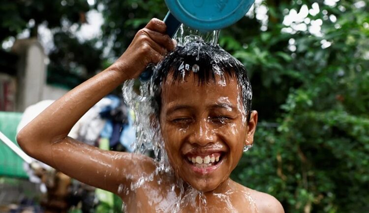 Một bé trai đổ nước lên đầu để giải nhiệt ở khu vực đông dân ở Jakarta hôm 16/5/2024. Ảnh: Willy Kurniawan/Reuters