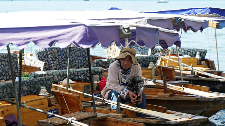 Người chèo thuyền cầm quạt tích điện tại Hàng Châu ngày 2/8. Ảnh: Reuters