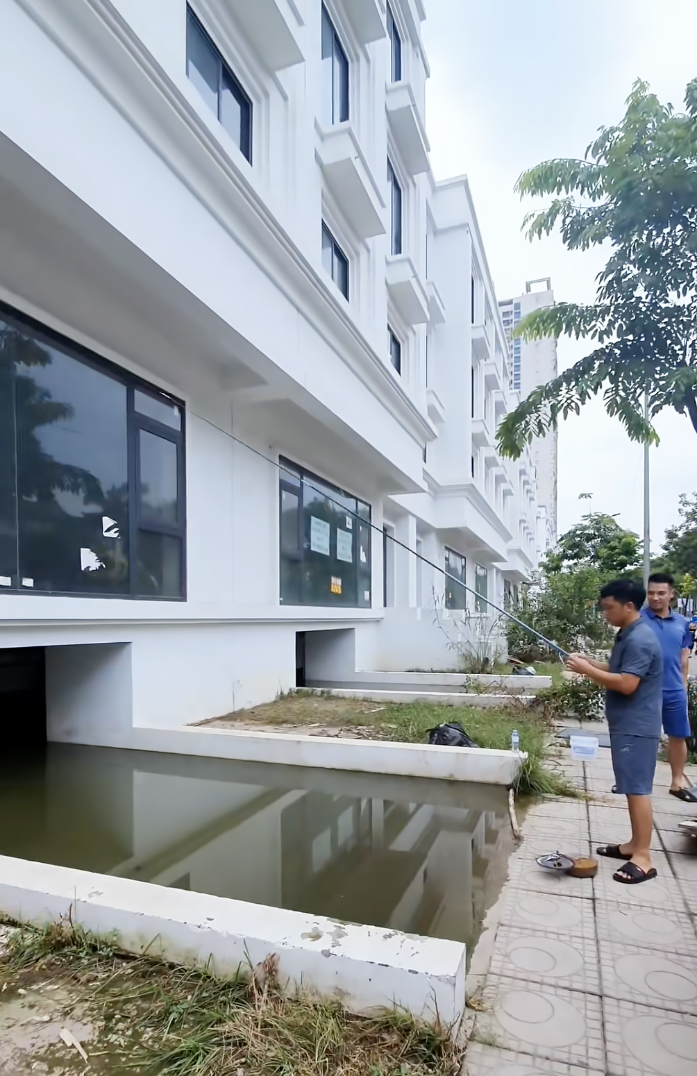 Một người đàn ông câu cá rô trong các hầm để xe của dãy biệt thự, shophouse trên đường Lê Trọng Tấn, huyện Hoài Đức, chiều 28/7. Ảnh: Phạm Hà
