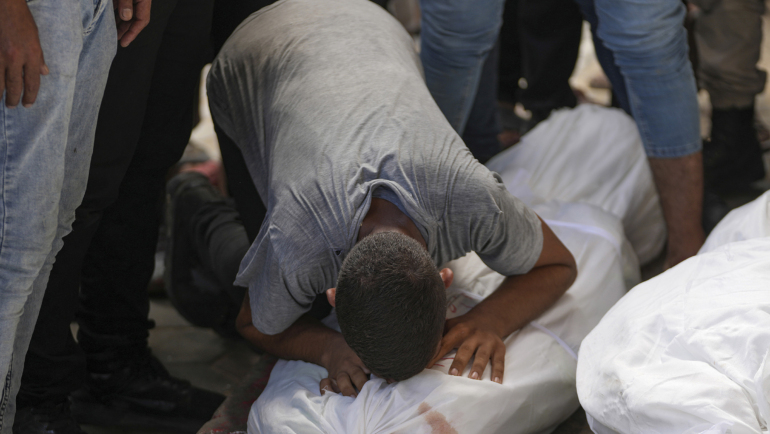 Người Palestine ôm thi thể thân nhân thiệt mạng trong vụ không kích ở miền trung Dải Gaza ngày 17/8. Ảnh: AP