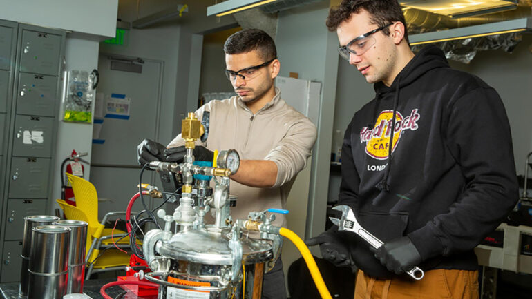 Hai nhà nghiên cứu MIT Aly Kombargi (trái) và Niko Tsakiris (phải) với lò phản ứng hydro mới. Ảnh: Tony Pulson