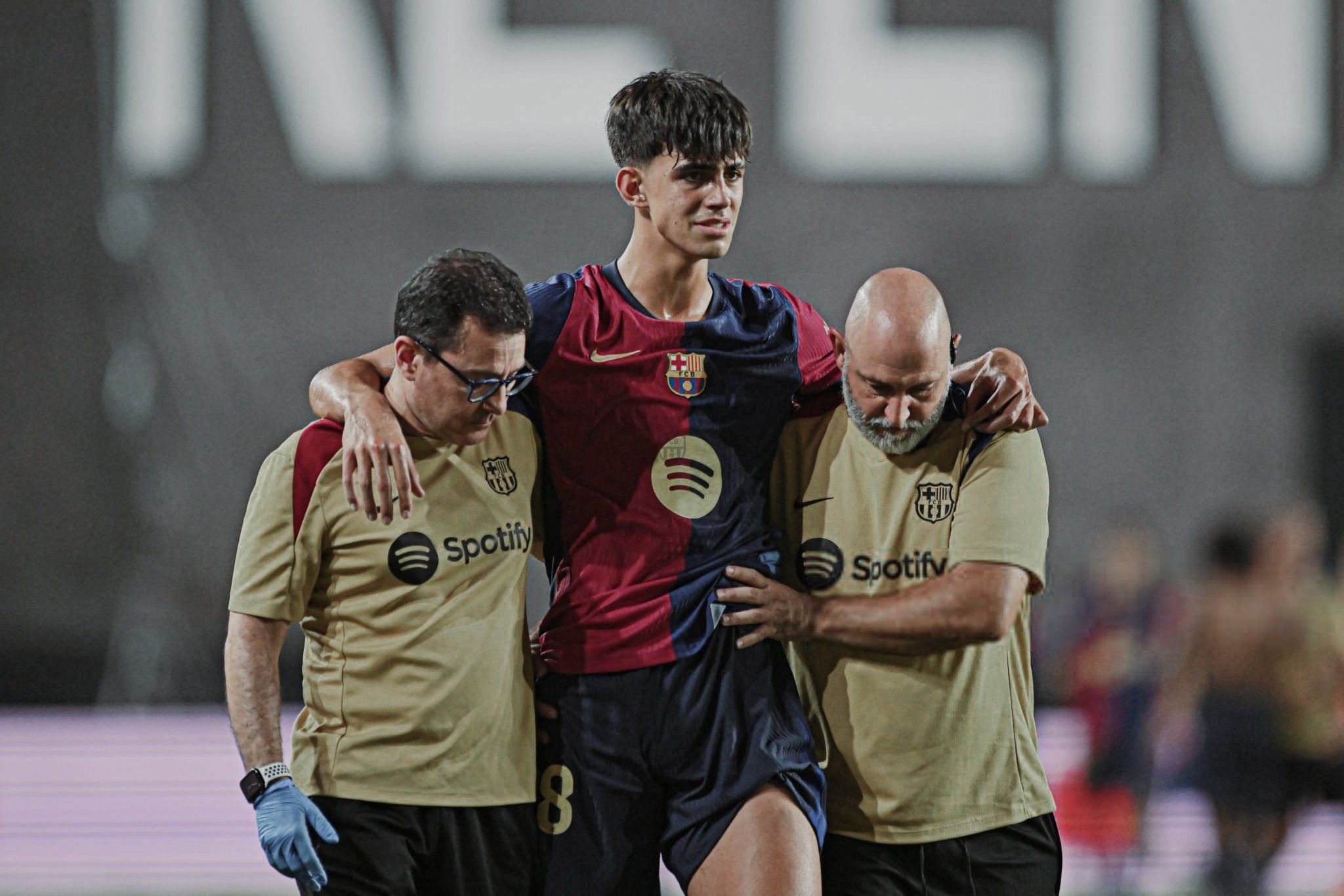 Bernal (giữa) được dìu rời sân cuối trận Rayo - Barca tối 27/8. Ảnh: EFE