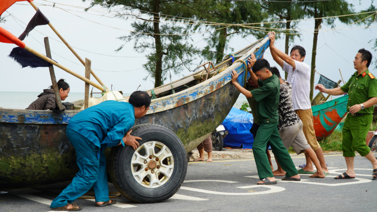 Ngư dân và lực lượng chức năng Sầm Sơn kéo thuyền vào bãi tập kết chiều 6/9. Ảnh: Lê Hoàng