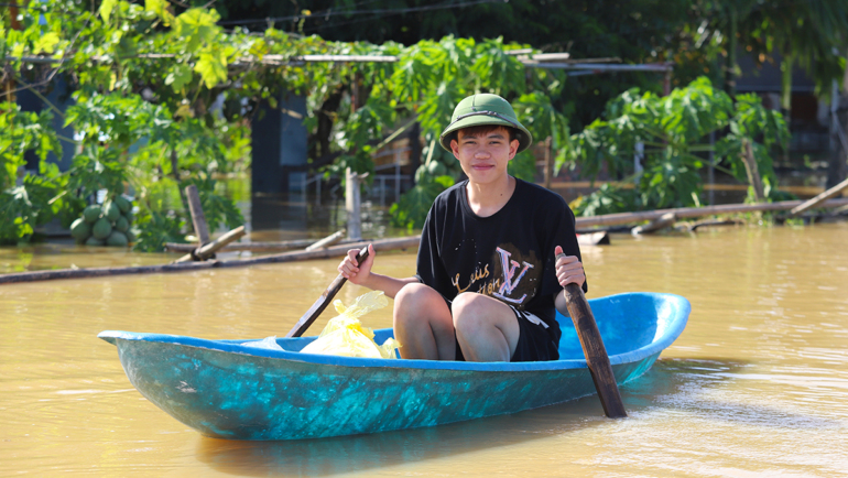 Kiên đang chèo thuyền đi đưa hàng cứu trợ cho người dân thôn 9, chiều 12/9. Ảnh: Đức Hùng