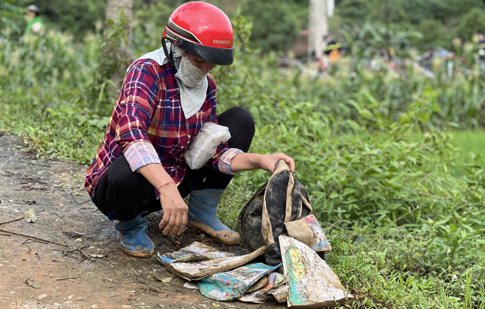 Người thân bên cặp sách còn sót lại của học trò Làng Nủ sau trận lũ quét rạng sáng 10/9. Ảnh: Hoàng Phương