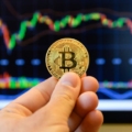 Nhà đầu tư đang cầm biểu trưng Bitcoin trước màn hình theo dõi thị giá. Ảnh: CNBC